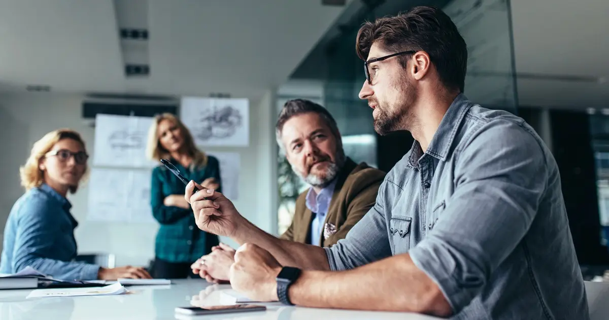 Young designer giving some new ideas about project to his partners in conference room. Business people discussing over new business project in office